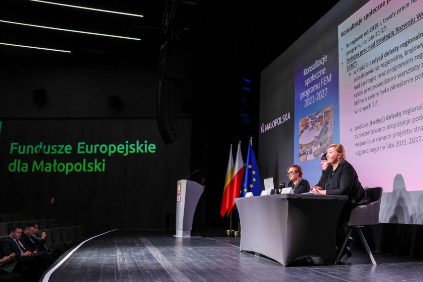 W tle wyświetlana jest prezentacja. Na bocznej ścianie wyświetlany jest logotyp Funduszy Europejskich dla Małopolski.