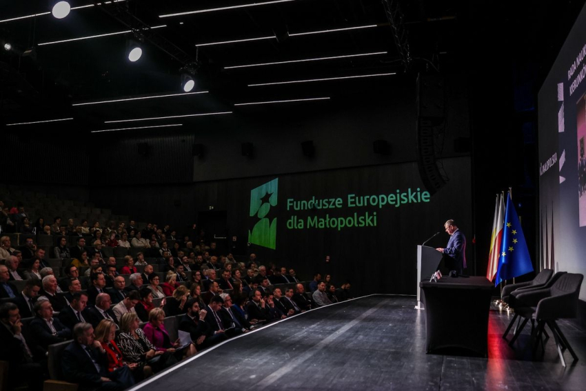 Na bocznej ścianie wyświetlany jest logotyp Funduszy Europejskich dla Małopolski.