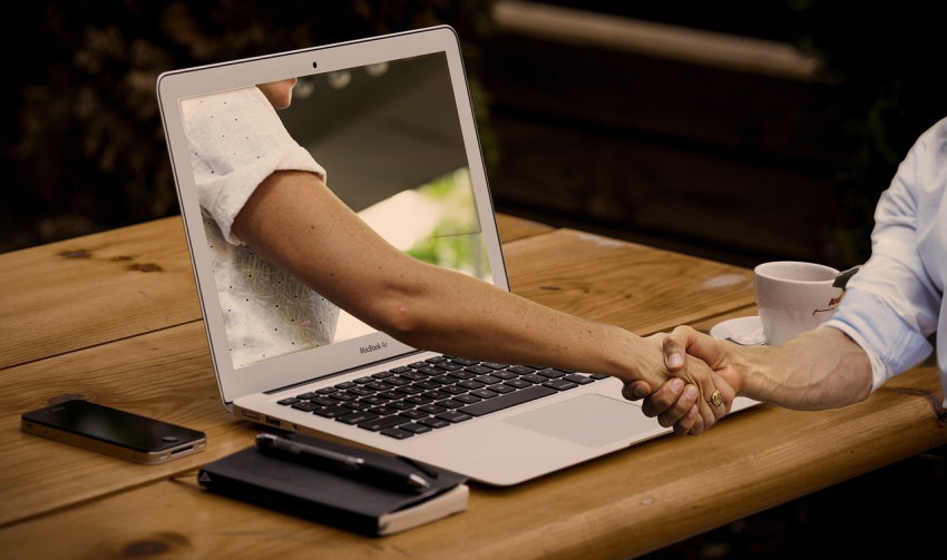 Laptop i ręce w uścisku gratulacji.