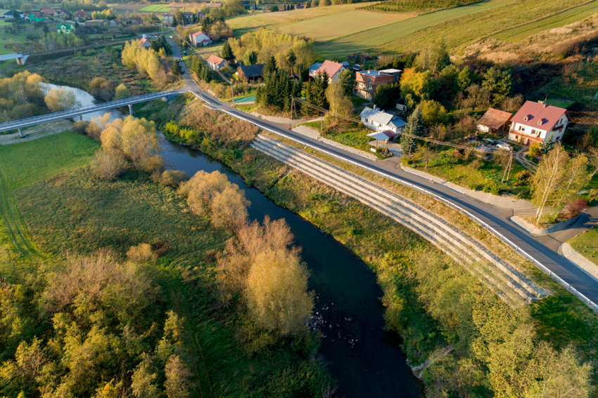 zabezpieczone osuwisko nad rzeką. Droga a przy niej domy mieszkalne