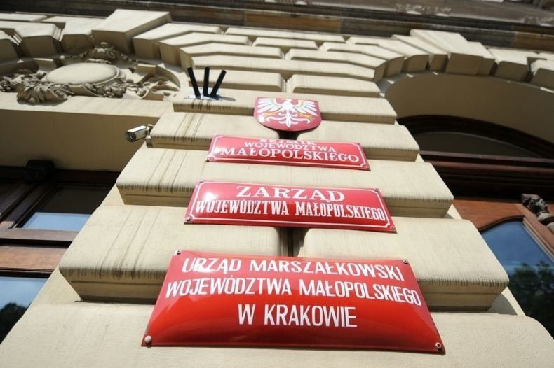 Fragment budynku z czerwonymi tablicami informującymi, że mieści się w nim Urząd Marszałkowski Województwa Małopolskiego.