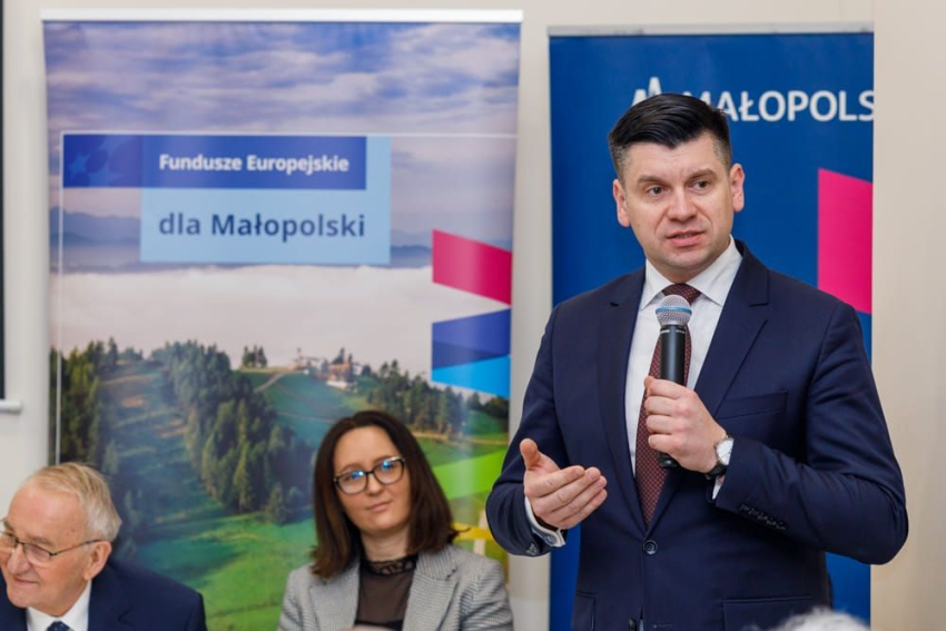 Wicemarszałek Łukasz Smółka trzyma w ręce mikrofon i przemawia.