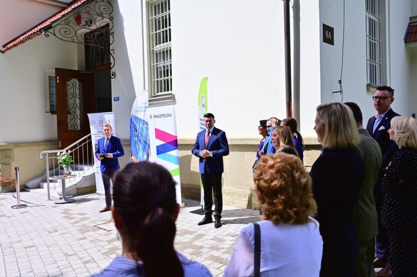 Grupa osób stojąca przed budynkiem.