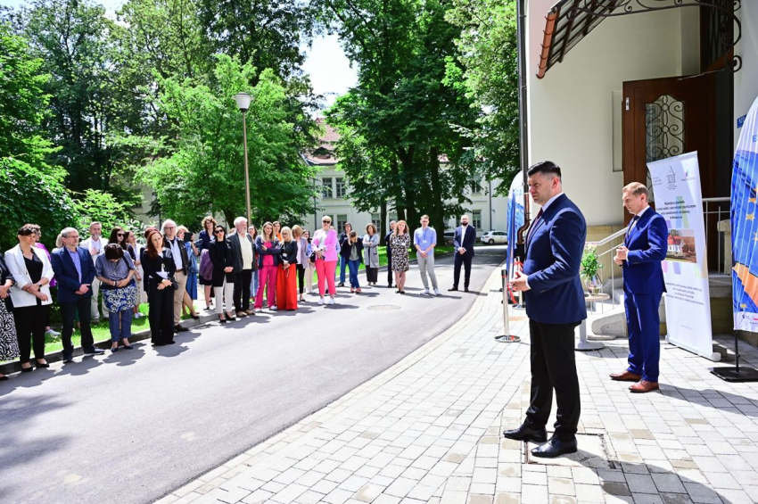 Grupa osób stojąca przed budynkiem w parku.