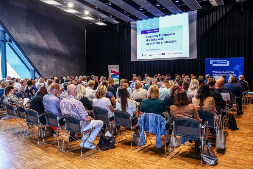 Ludzie w sali konferencyjnej oglądający prezentację na rzutniku.