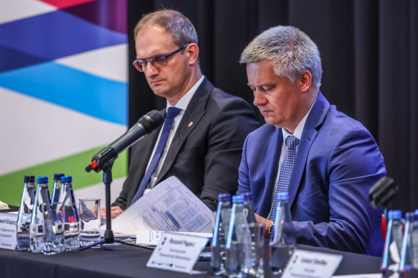 Dwóch mężczyzn siedzi przy stole konferencyjnym.