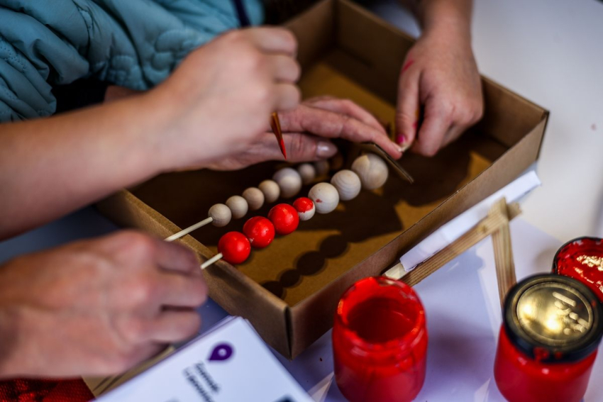 Malowanie drewnianych korali czerwoną farbą.