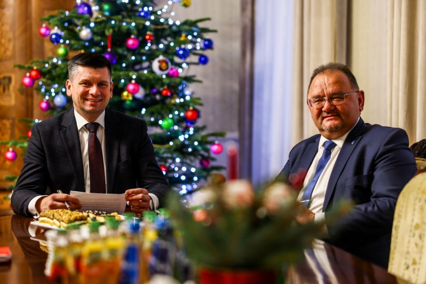 Marszałek Małopolski siedzi z uczestnikiem spotkania przy stole.