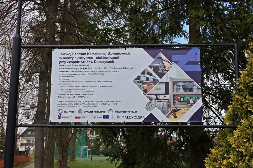 Tablica informacyjna przed budynkiem szkoły.