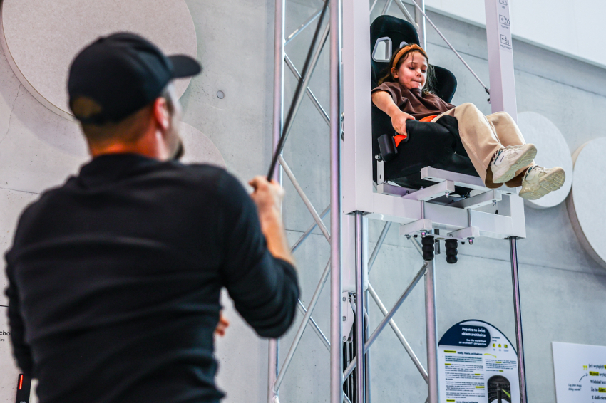 Wystawa stała w Cogiteonie. Dziewczynka na krześle, które jest podciągane na linię przez jej tatę.