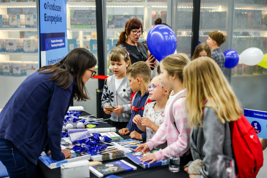 Konsultantka Punktu Informacyjnego Funduszy Europejskich rozmawia z dziećmi.