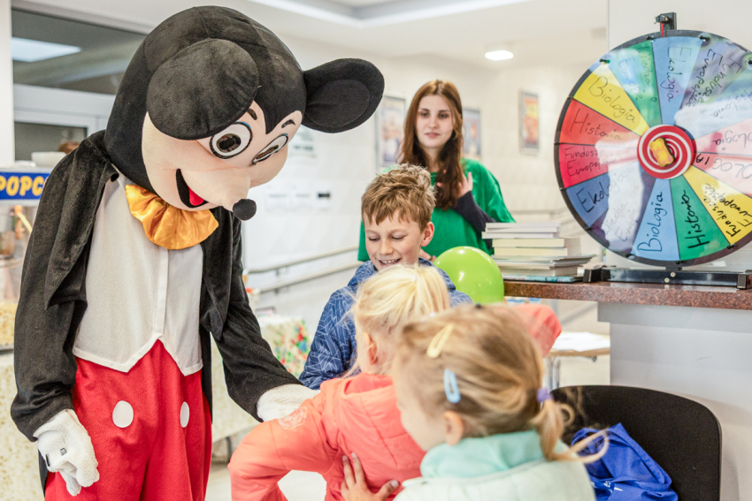 Dzieci bawiące się z człowiekiem przebranym w kostium Myszki Miki.
