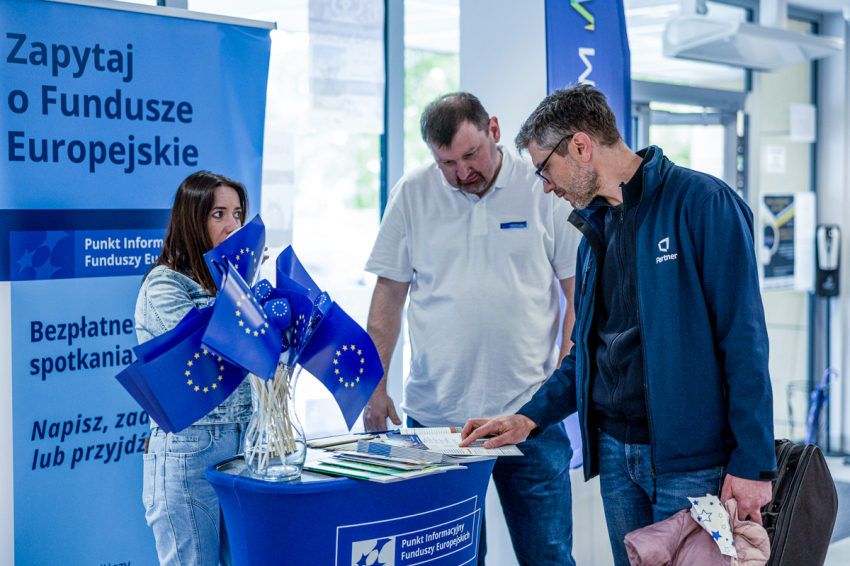 Konsultanci Punktu Informacyjnego Funduszy Europejskich rozmawiają z panem przy stoisku funduszowym.