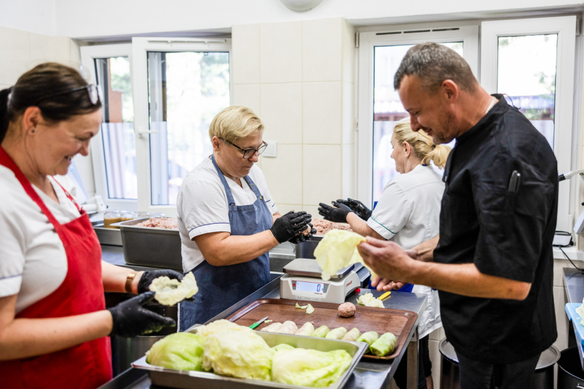 3 kobiety i mężczyzna przygotowują potrawę - gołąbki.