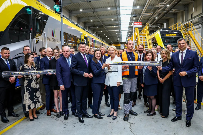 Uczestnicy wydarzenia przy składzie kolejowym. Wśród nich, Marszałek Łukasz Smółka, Pani Iwona Gibas, Wicemarszałek Ryszard Pagacz.