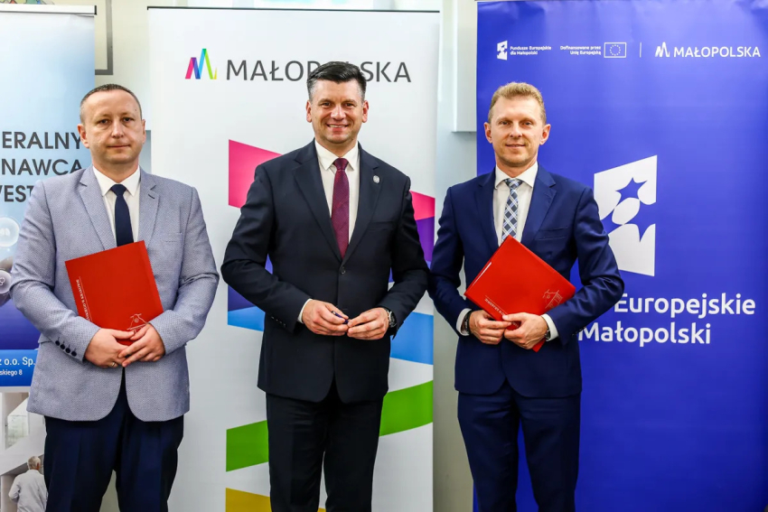 Marszałek Łukasz Smółka, Michał Tochowicz i przedstawiciel wykonawcy umowy prezentują podpisane dokumenty.