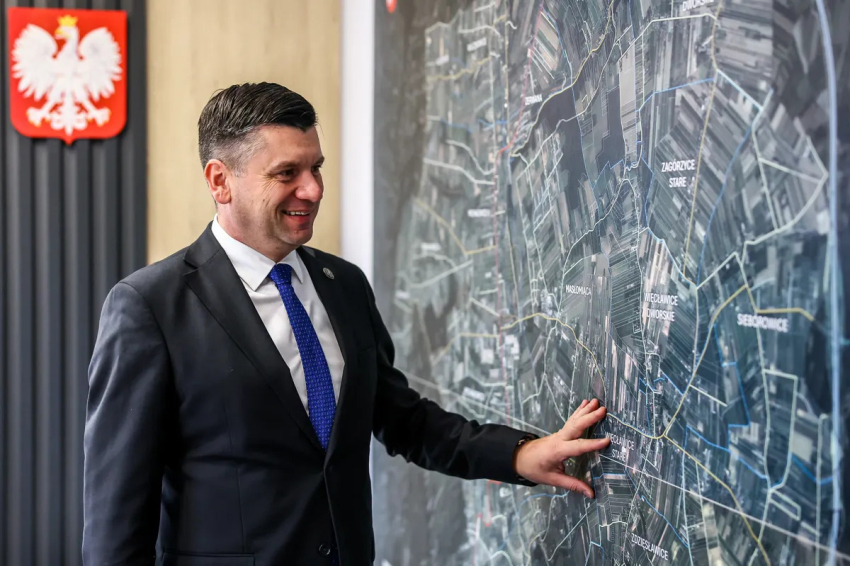Marszałek Łukasz Smółka przy wiszącej mapie.