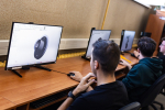 Trzech uczniów pracuje przy komputerach, tworząc modele 3D elementów technicznych