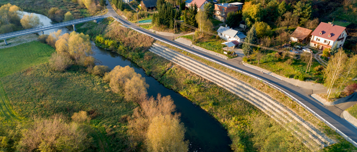zabezpieczone osuwisko nad rzeką. Droga a przy niej domy mieszkalne