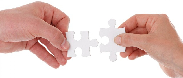 Dłonie trzymające pojedyncze puzzle.