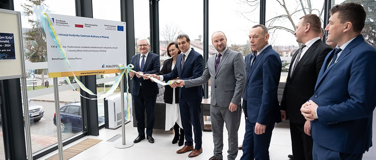 Uczestnicy wydarzenia uroczyście zciągają wstęgę z tablicy informacyjnej