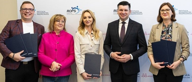 Uczestnicy wydarzenia stoją na tle ścianki z napisami Małopolska Ekonomia Społeczna.
