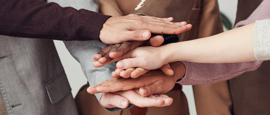 Dłonie kilku osób złożone jedne na drugich.