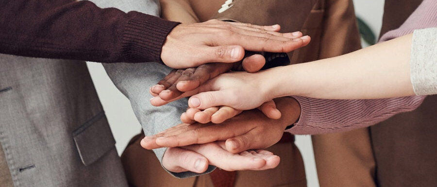 Dłonie kilku osób złożone jedne na drugich.
