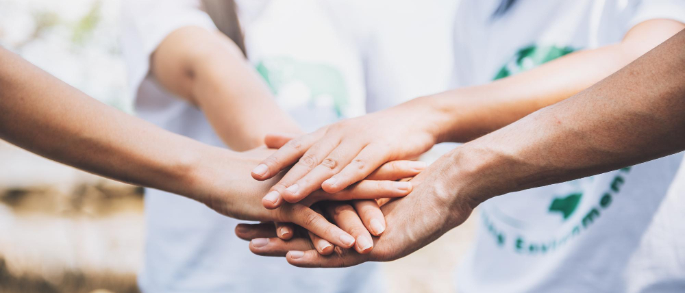 Dłonie kilku osób złożone jedne na drugich.