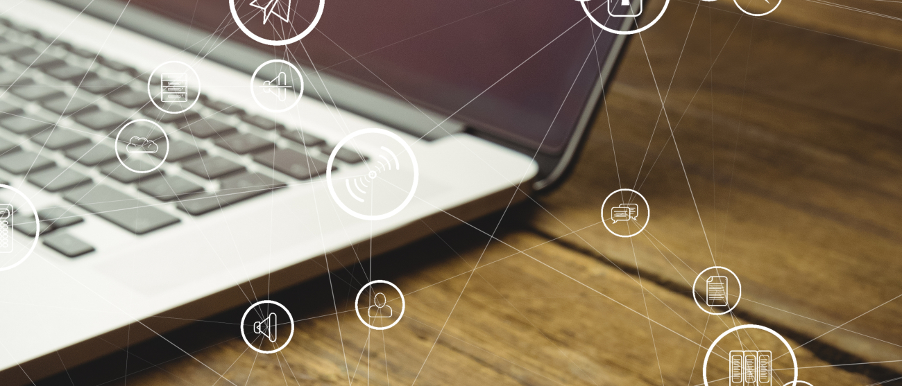 Fragament laptopa na biurku z wirtualnymi ikonkami telefonicznymi w tle.