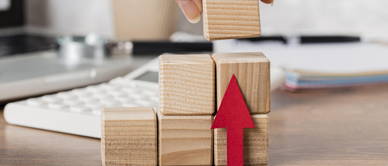 Drewniane klocki z czerwoną strzałką w górę symbolizującą wzrost.