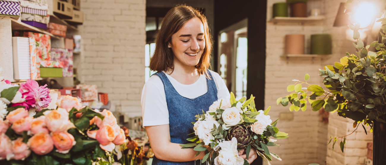 Kobieta robi bukiet w swojej kwiaciarni.