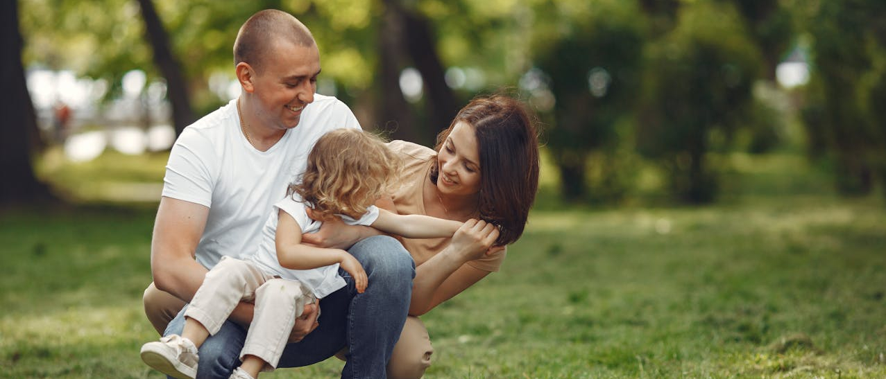 Rodzice z małą dziewczynką w parku.