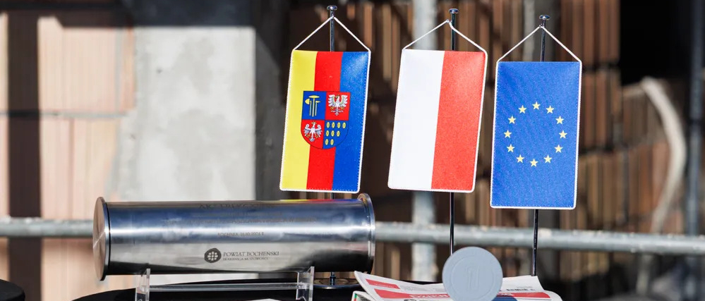 Akt w metalowej tubie, flagi: Polski, Unii Europejskiej i powaitu bocheńskiego